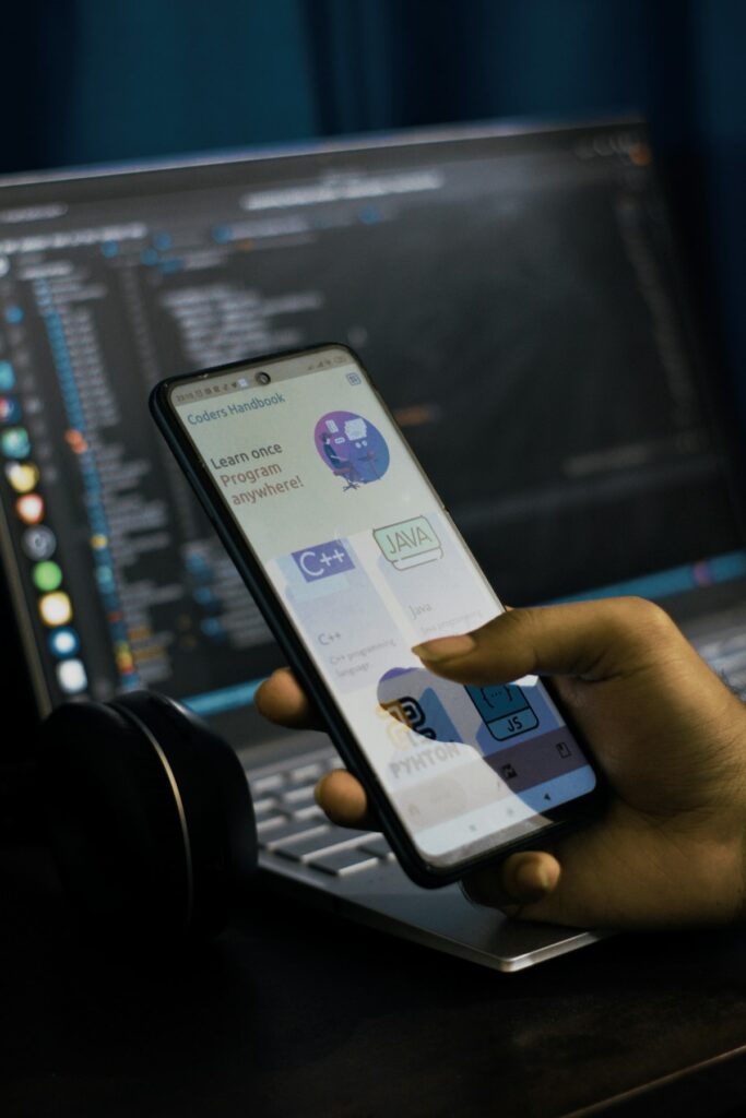 Person som håller en mobiltelefon framför en bärbar dator