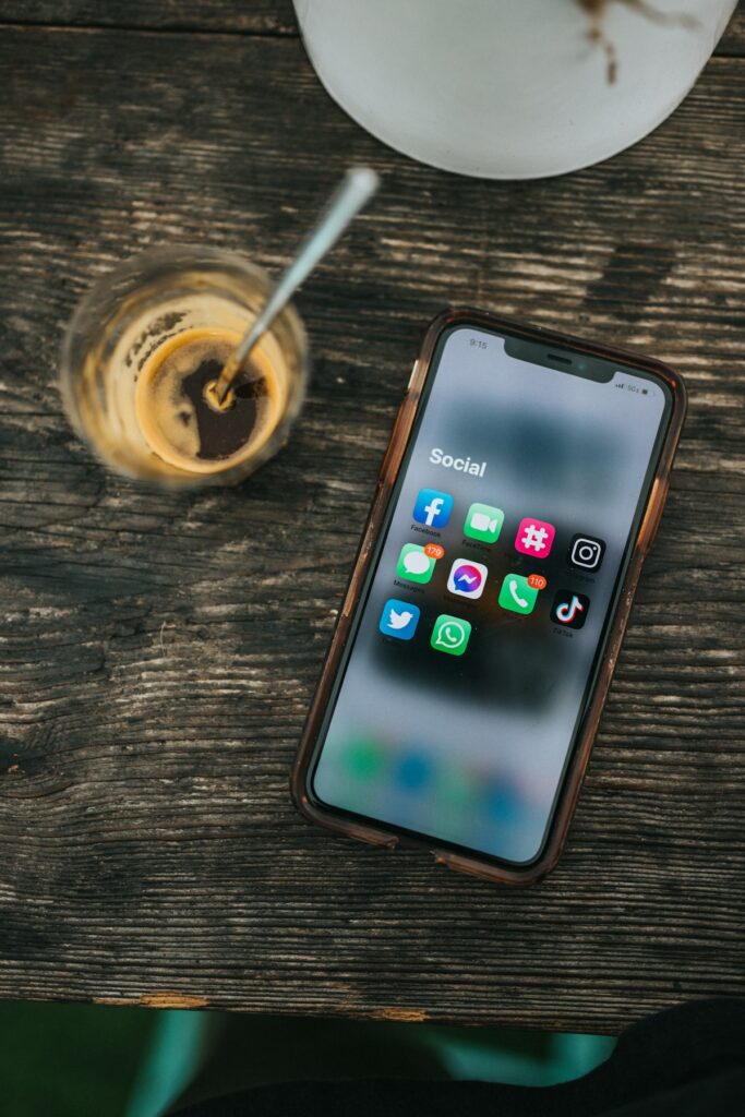 Mobiltelefon med sociala medier-ikoner bredvid en kaffekopp